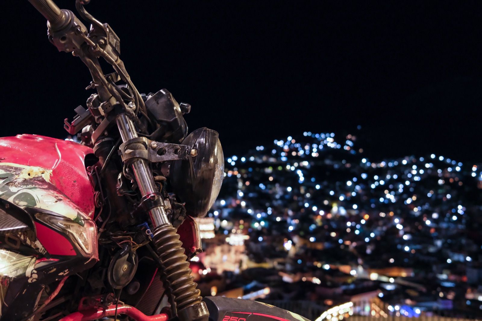 A motorcycle overlooking a hillside city at night