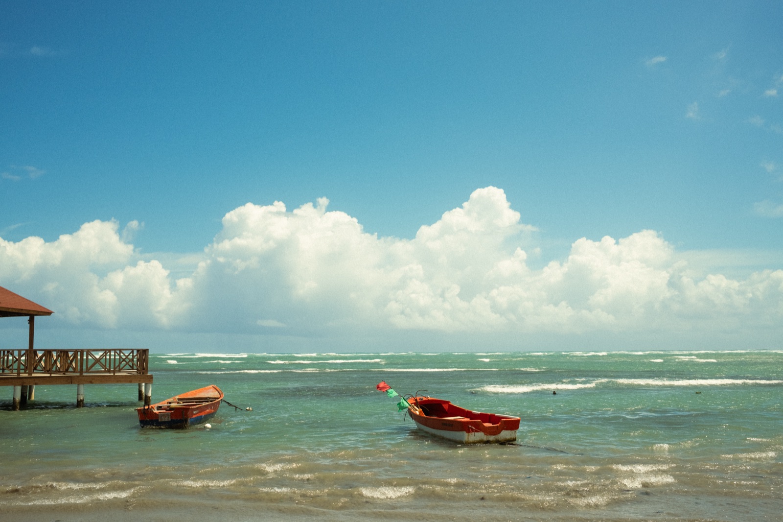 Small boats on turquoise water under big clouds